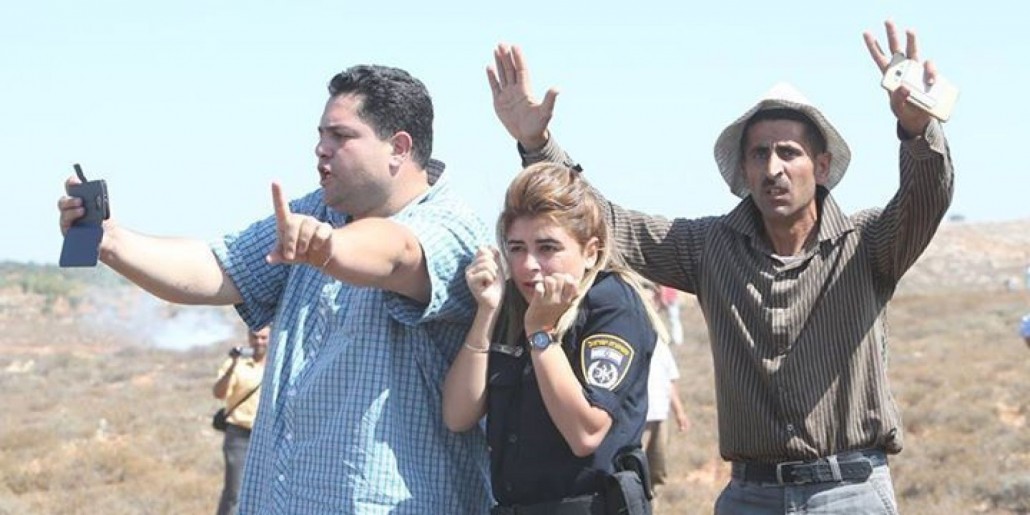 فلسطینیان از مامور پلیس اسرائیلی در مقابل شهرک نشینان یهودی افراطی محافظت می‌کنند. 