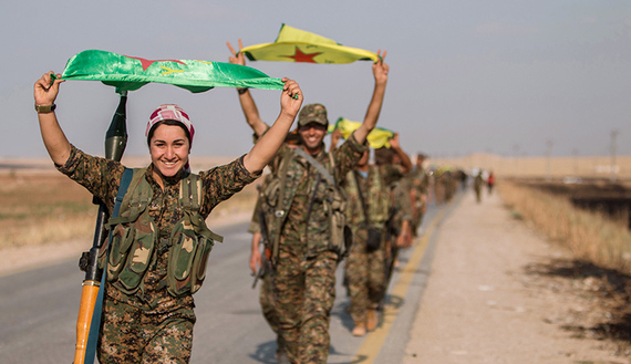Kurdish fighters gesture while carrying their parties' flags in Tel Abyad of Raqqa governorate after they said they took control of the area June 15, 2015. Syrian Kurdish-led forces said they had captured a town at the Turkish border from Islamic State on Monday, driving it away from the frontier in an advance backed by U.S.-led air strikes that has thrust deep into the jihadists' Syria stronghold. The capture of Tel Abyad by the Kurdish YPG and smaller Syrian rebel groups means the Syrian Kurds effectively control some 400 km (250 miles) of the Syrian-Turkish border that has been a conduit for foreign fighters joining Islamic State. Picture taken June 15, 2015. REUTERS/Rodi Said TPX IMAGES OF THE DAY - RTX1GPFR